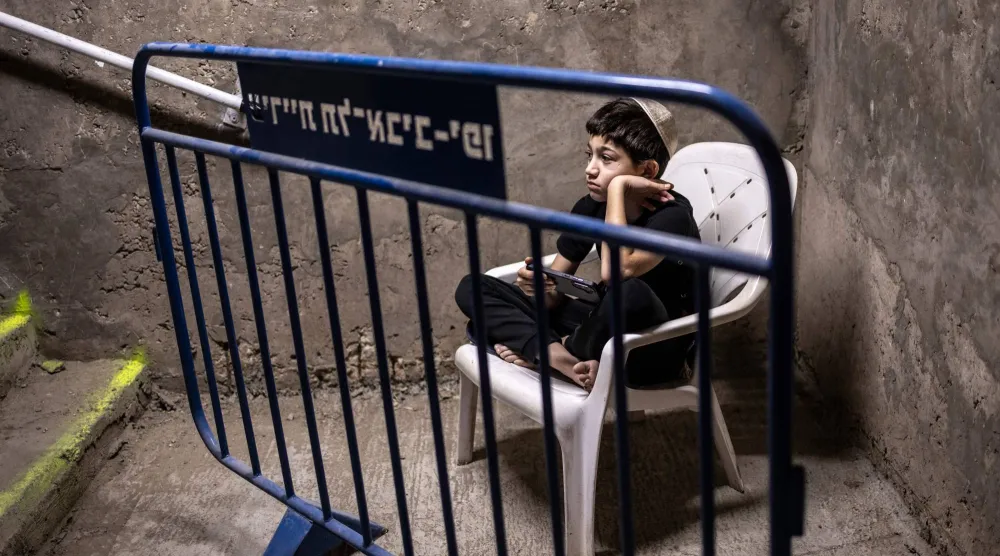 طفل في تل أبيب يراقب الوضع وهو ينتظر في موقف سيارات تحت الأرض يُستخدم كملجأ من القنابل يوم الثلاثاء (أ.ف.ب)