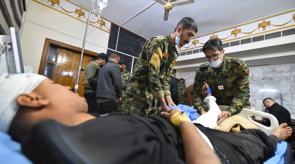 عناصر من «الحشد الشعبي» يعالجون زميلاً لهم جُرح في قصف استهدف أحد مقارهم جنوب الموصل (رويترز)