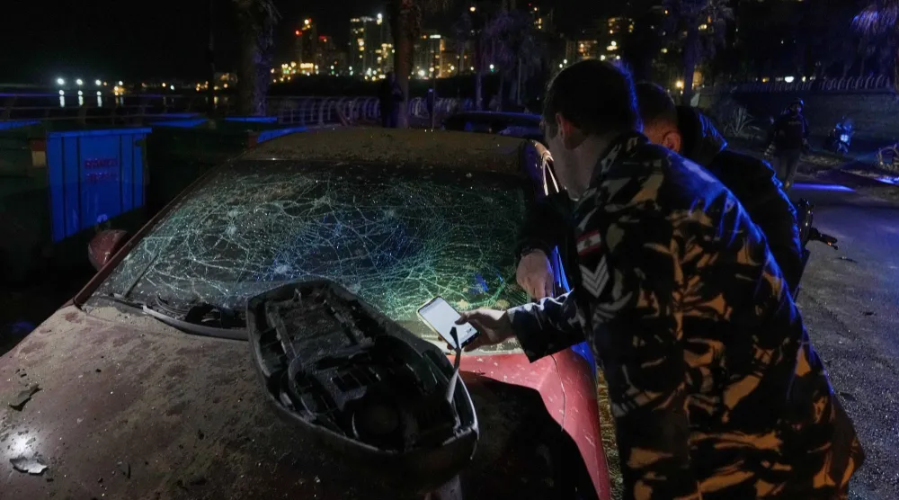 رجل أمن يتفقد سيارة متضررة جراء غارة إسرائيلية على منطقة الرملة البيضاء في بيروت (ا.ب)
