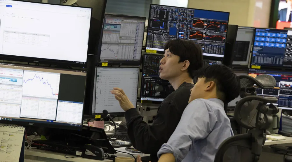 متداولون كوريون جنوبيون يعملون أمام شاشات تعرض مؤشرات الأسهم في بنك هانا في سيول (إ.ب.أ)