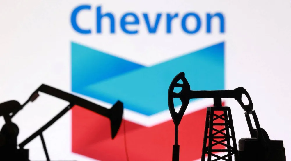 صورة توضيحية تظهر رافعات مضخات النفط مطبوعة بتقنية الطباعة ثلاثية الأبعاد وشعار شركة «شيفرون» (رويترز)