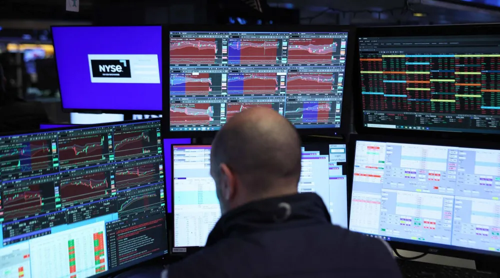 متداول يراقب شاشات تعرض مؤشرات الأسهم في بورصة نيويورك (أ.ف.ب)