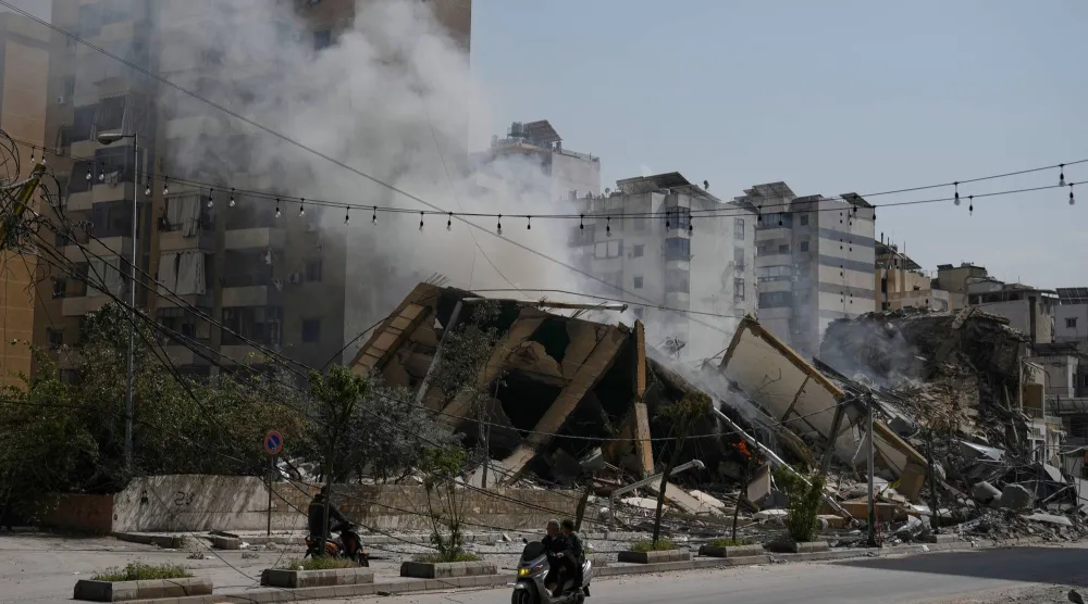 رجل على دراجة نارية يَعبر أمام بناء مدمَّر في ضاحية بيروت الجنوبية (أ.ب)