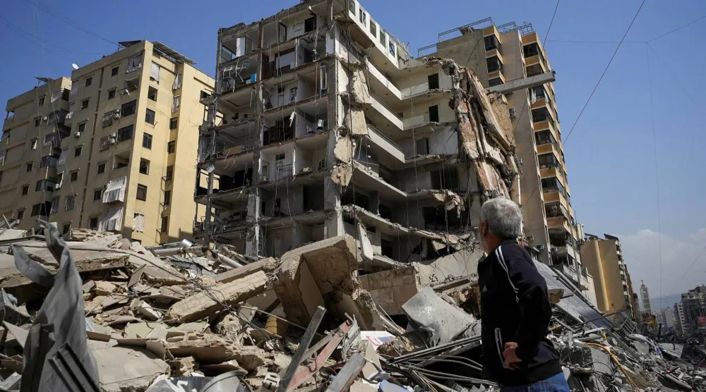 لبناني يسير قرب ركام مبانٍ دمرتها غارات إسرائيلية في ضاحية بيروت الجنوبية (رويترز)