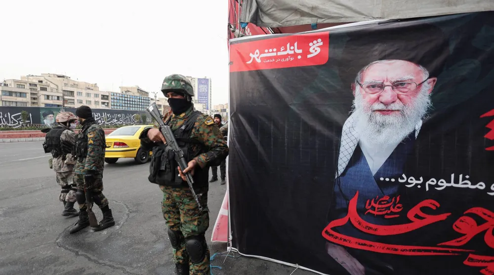 أفراد من الشرطة يقفون حراساً في أحد شوارع العاصمة الإيرانية طهران بجوار لافتة كبيرة تحمل صورة المرشد الإيراني الراحل علي خامنئي... 12 مارس 2026 (رويترز)
