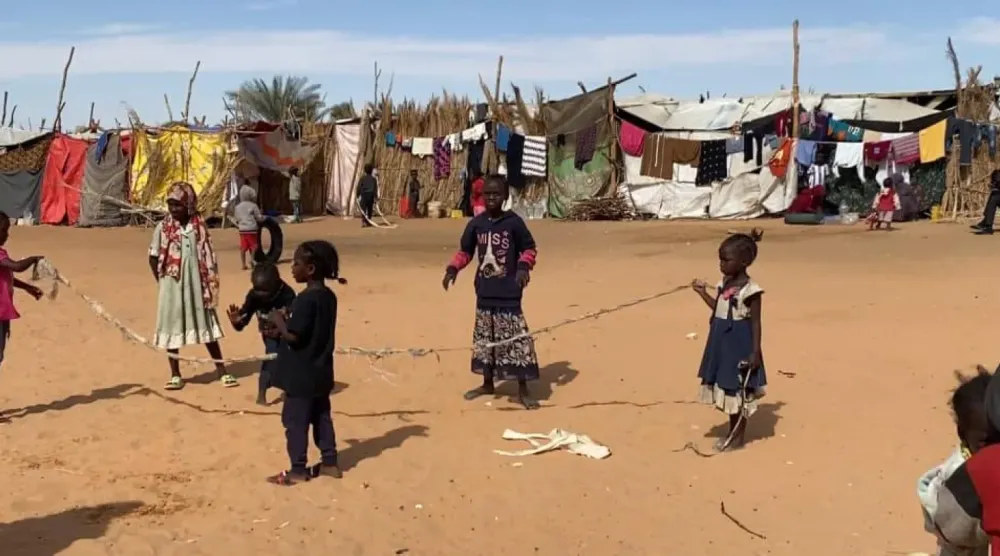 أطفال يلعبون أمام خيام للنازحين السودانيين على أطراف مدينة الكفرة الليبية (الصفحة الرسمية لبلدية المدينة)