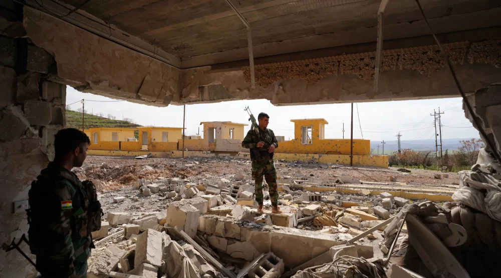 مسلح تابع لحزب الحرية الكردستاني داخل منزل عائلي دُمّر بسبب الغارات في مخيم بأربيل (د.ب.أ)