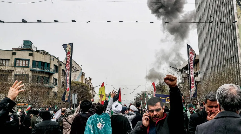  الدخان يتصاعد من موقع ضربة إسرائيلية في طهران بينما يحيي إيرانيون «يوم القدس» أمس (أ.ف.ب)