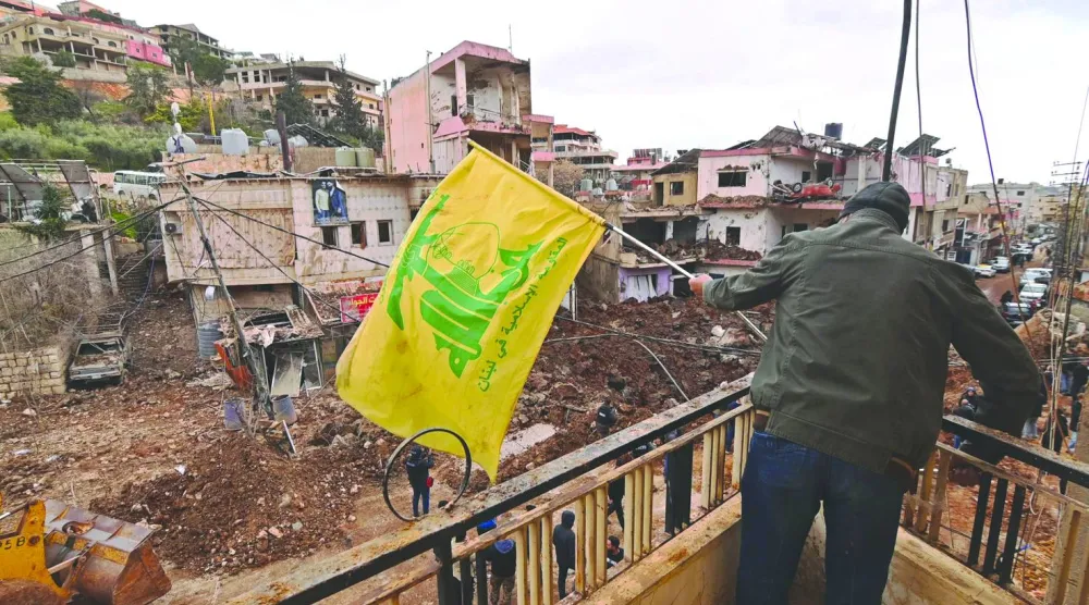 مواطن يرفع علم «حزب الله» في بلدة النبي شيت حيث قام الجيش الإسرائيلي بإنزال وأمطر البلدة بقصف كثيف موقعاً عشرات القتلى والجرحى (أ.ف.ب)