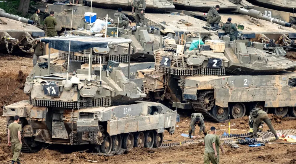 İsrail askerleri, Lübnan sınırına yakın kuzey İsrail'deki Yukarı Celile'de bir toplanma alanında tank paletlerini tamir ediyor (AFP) 