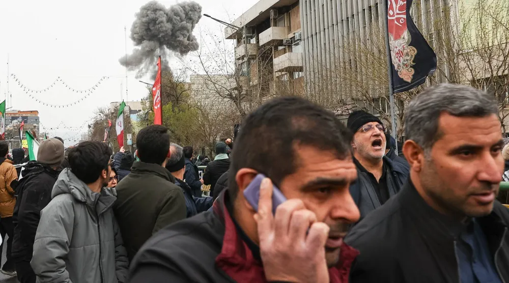 أدخنة تصعد في السماء خلف عدد من المواطنين في يوم القدس في طهران أمس (أ.ب)