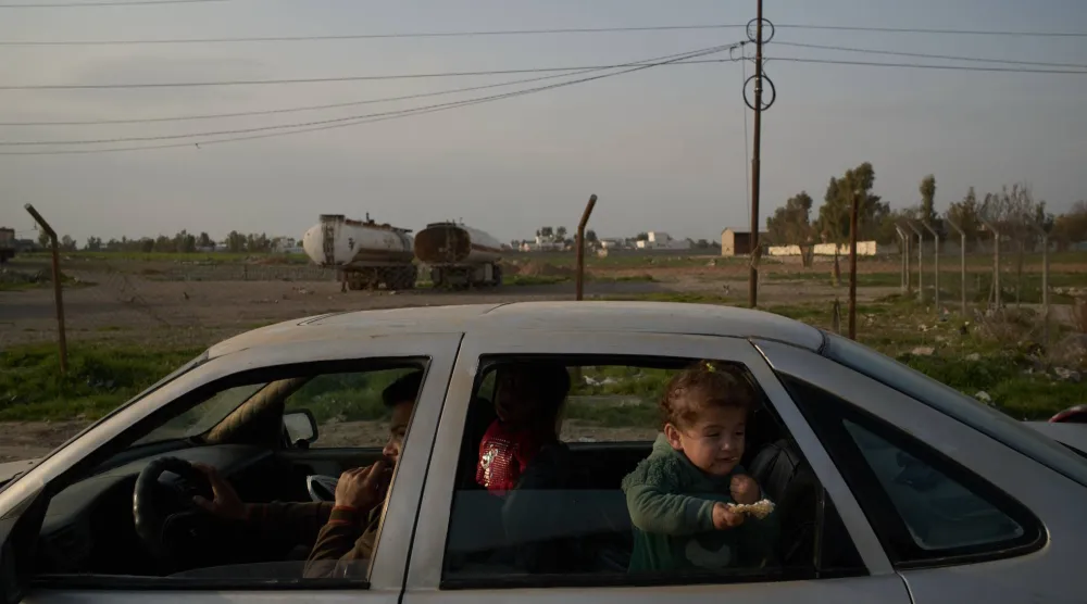 رجل برفقة أطفاله على طريق يمر بجانب شاحنات في ضواحي أربيل شمال العراق (أ.ب)