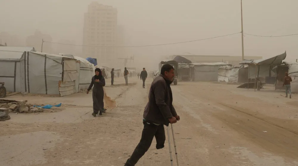 فلسطينيون يسيرون وسط العاصفة الرملية في خان يونس جنوب قطاع غزة السبت (أ.ب)