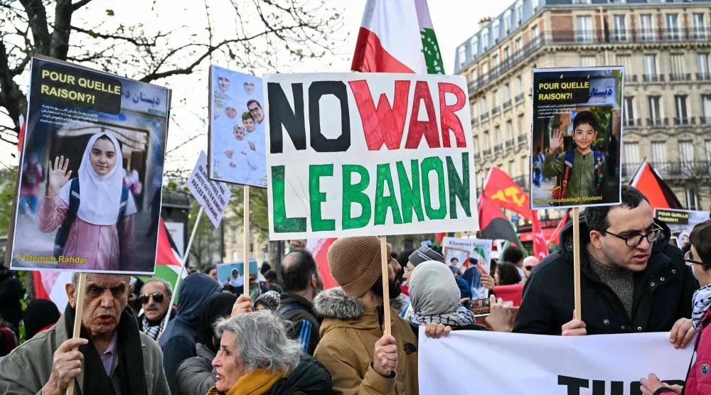 ناشطون في باريس يرفعون لافتة تدعو لوقف الحرب في لبنان خلال حراك ضد الحرب في الشرق الأوسط (أ.ف.ب)