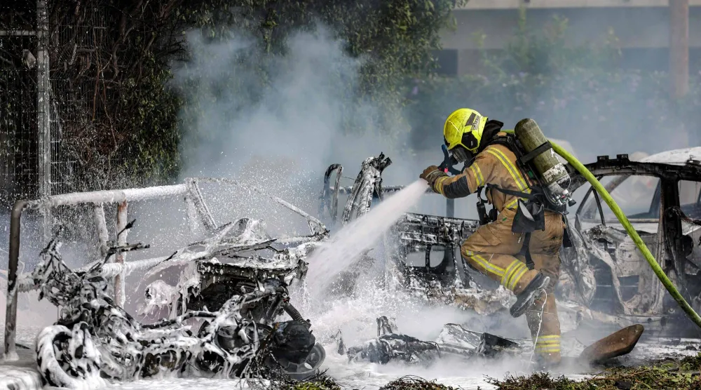 رجل إطفاء يُخمد حريقاً اندلع في سيارة إثر اصطدام قذيفة بها جراء غارة إيرانية جنوب تل أبيب (أ.ف.ب)