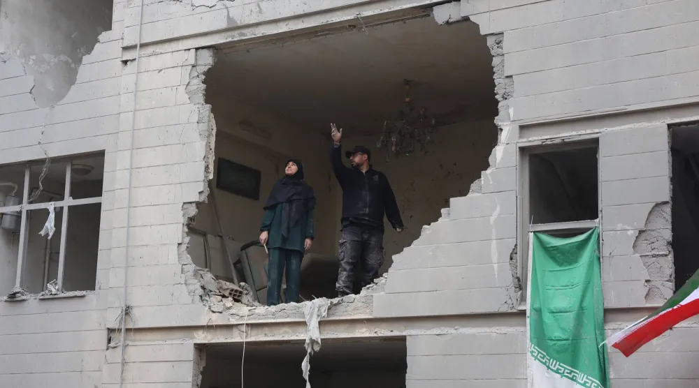 إيرانيان يقفان في منزلهما المدمر جزئياً جنوب طهران (إ.ب.أ)