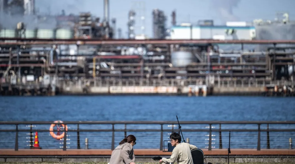 رجل يعزف على الغيتار في حديقة هيغاشي-أوغيشيما هيغاشي في منطقة كيهين الصناعية، في خليج طوكيو والتي تضم عمليات تكرير النفط (أ.لف.ب)