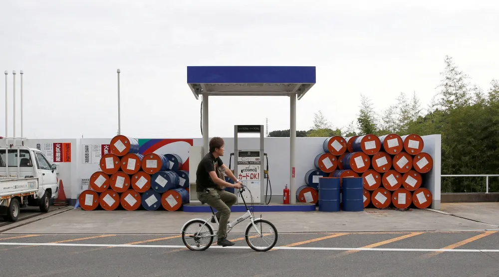 رجل يمر بدراجته الهوائية أمام محطة وقود في مدينة سوزوكا، اليابان (رويتزر)