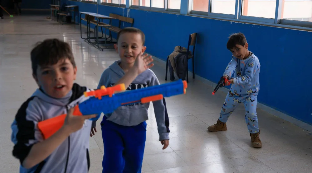 أطفال بمسدسات بلاستيكية في إحدى المدارس التي تحولت إلى مركز إيواء في بيروت (رويترز)