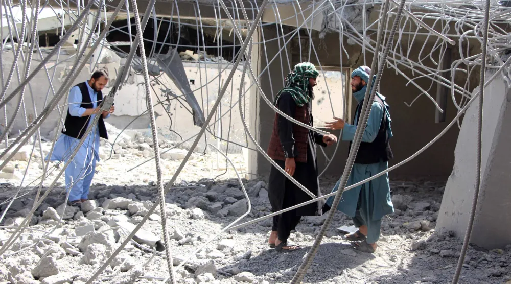 أشخاص يتفقدون الأضرار الناجمة عن قصف منطقة متضررة في قندهار بجنوب أفغانستان الأحد (إ.ب.أ)