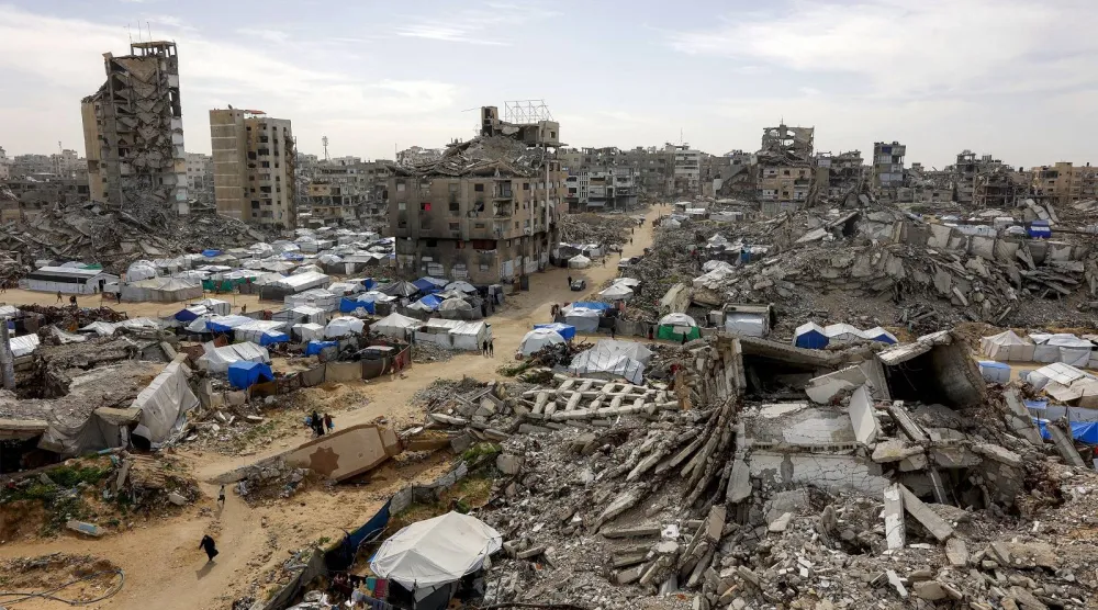 خيام تؤوي فلسطينيين نازحين إلى جانب مبانٍ مدمرة في مدينة غزة (أ.ف.ب)