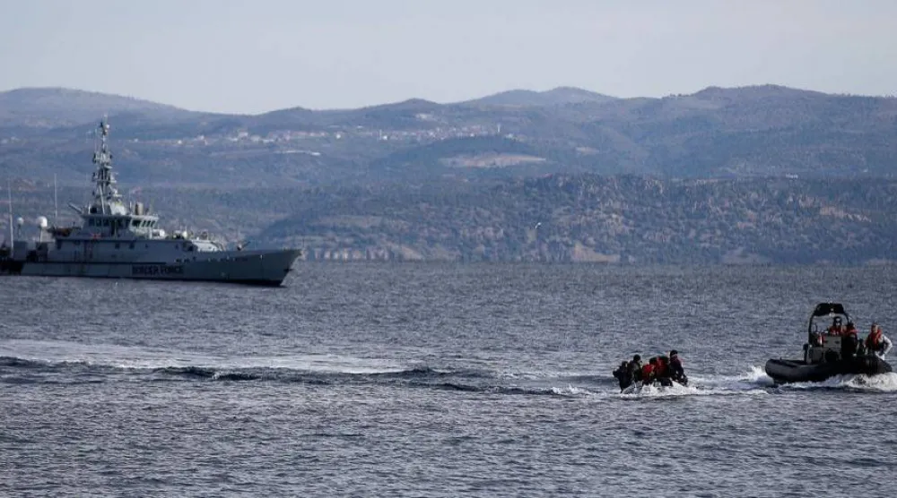 قارب إنقاذ يرافق قارباً صغيراً يحمل مهاجرين بينما تقوم سفينة تابعة لوكالة حرس الحدود الأوروبية «فرونتكس» بدورية في الخلفية قبالة جزيرة ليسبوس اليونانية (رويترز - أرشيفية)