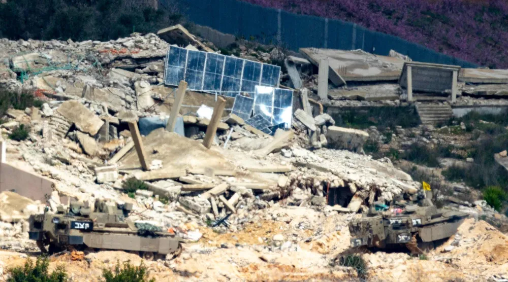 مركبات قتالية إسرائيلية تشق طريقها وسط قرية مدمرة في جنوب لبنان أمس (أ.ف.ب)