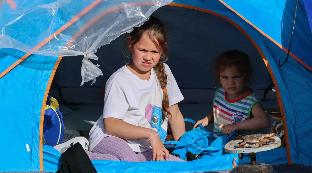 طفلان يلوذان إلى خيمة تأوي النازحين من الضاحية الجنوبية في وسط بيروت (إ.ب.أ)