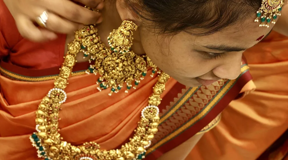 امرأة هندية تجرب حلياً ذهبية بمتجر مجوهرات في مدينة بنغالور (إ.ب.أ)