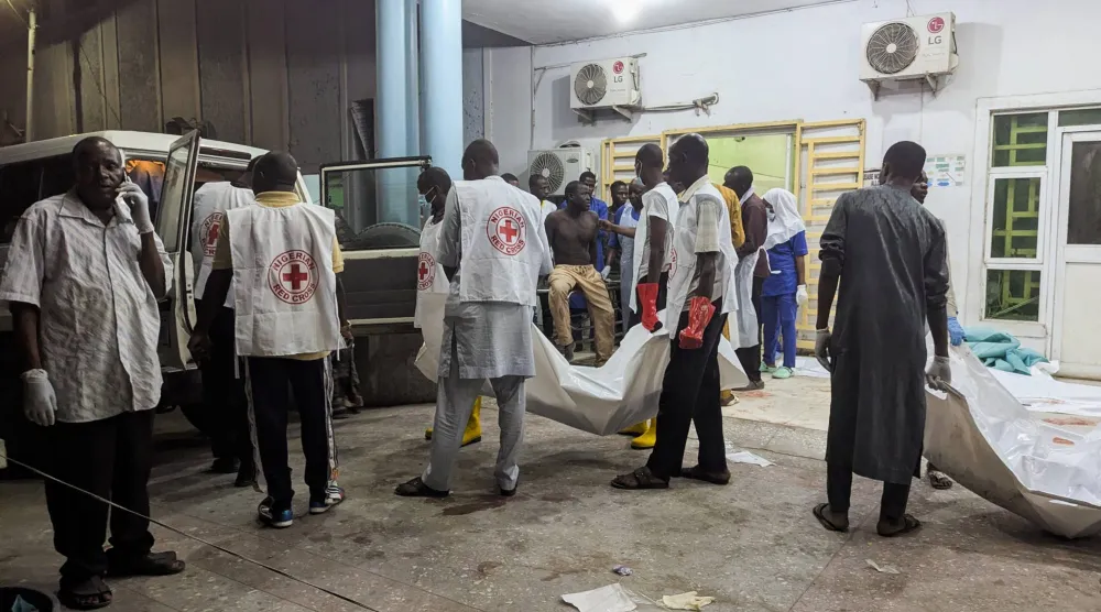 أفراد من «الصليب الأحمر» النيجيري ينقلون جثامين ضحايا في مستشفى بمايدوغوري ‌أمس (رويترز)