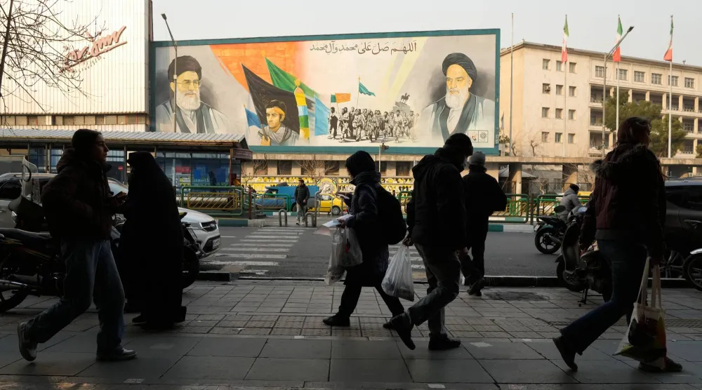 People walk in front of a mural depicting the late Iranian revolutionary founder Khomeini, right, members of the Basij paramilitary force and Supreme Leader Ali Khamenei along Enqelab-e-Eslami Street in Tehran, Iran, Sunday, Jan. 25, 2026. (AP Photo/Vahid Salemi)