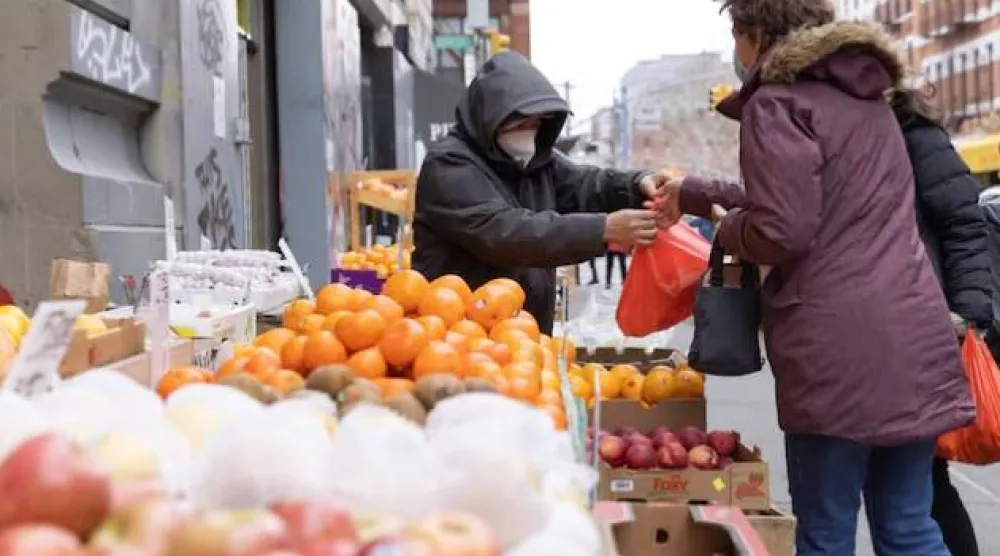 شخص يعمل في كشك لبيع الفواكه والخضراوات في مانهاتن بنيويورك (رويترز)