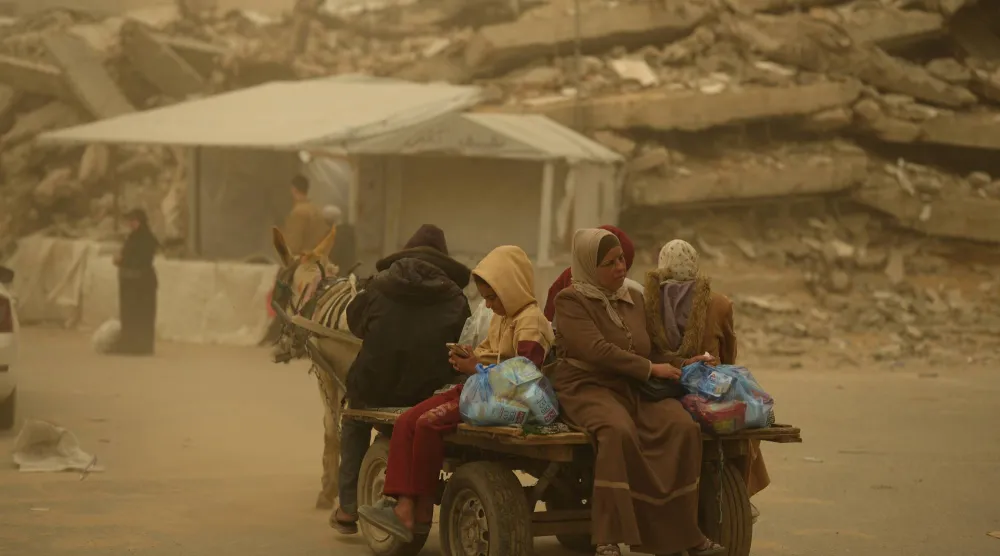 فلسطينيون يركبون عربة يجرها حمار وسط عاصفة رملية في مدينة غزة (أ.ب)