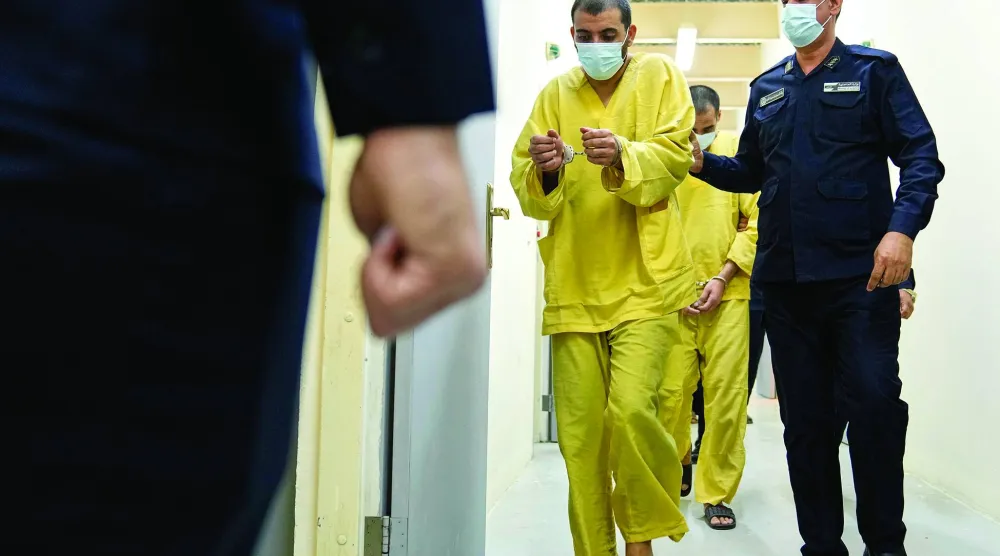 رجل أمن عراقي مع مشتبه فيه بالانتماء إلى «داعش» في سجن الكرخ ببغداد (أ.ب)