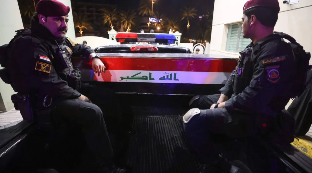 أفراد من الأمن الراقي إلى جانب نعش أحد عناصر الحشد الشعبي الذي قُتل بهجوم في قضاء القائم (أ.ف.ب)