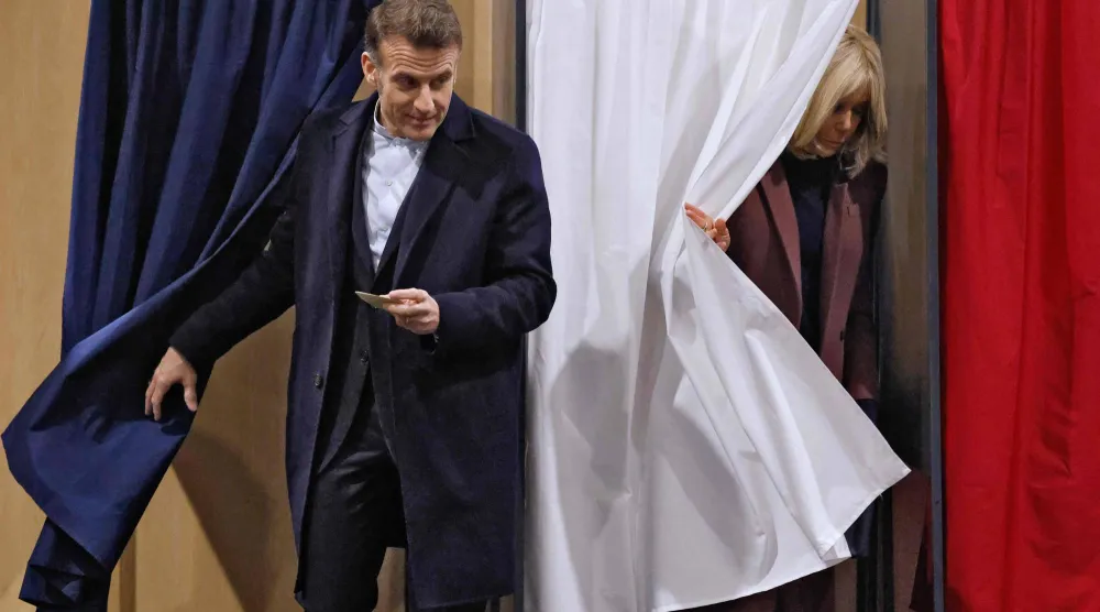 الرئيس الفرنسي إيمانويل ماكرون وزوجته بريجيت بعد اقتراعهما في الانتخابات المحلية بمدينة لو توكيه في شمال فرنسا (أ.ف.ب)