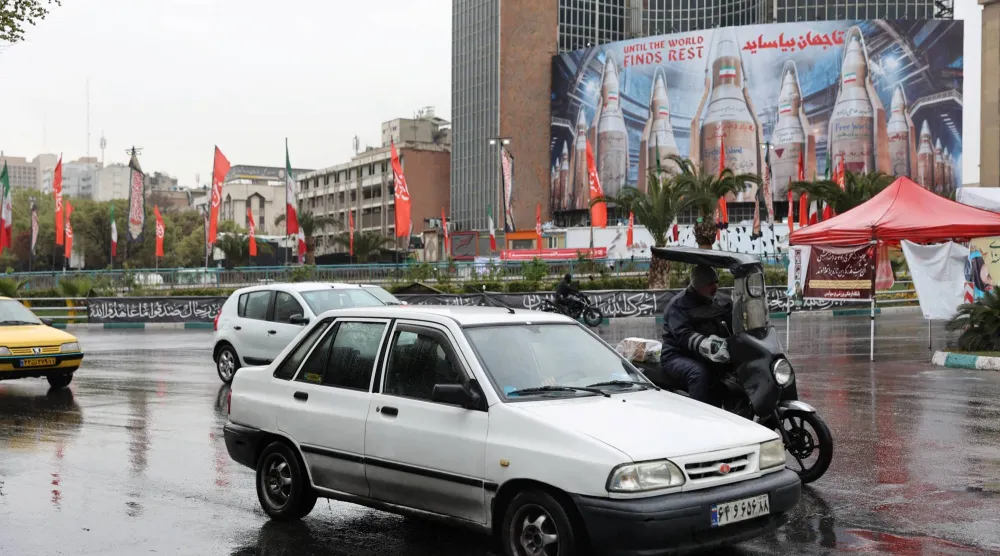 مركبات تسير بالقرب من لوحة إعلانية تحمل صورة صواريخ إيرانية في طهران يوم 16 مارس 2026 (رويترز)