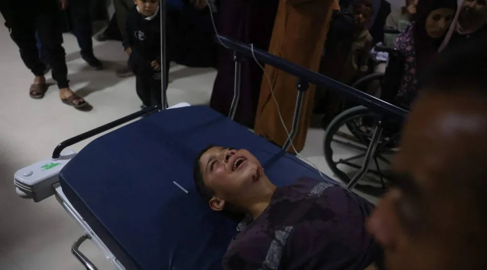 رجل يهرع حاملاً طفلاً يُقال إنه أصيب في غارة إسرائيلية إلى مستشفى ناصر بخان يونس الثلاثاء (أ.ب)