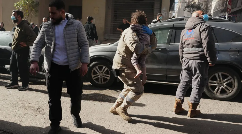 عامل إنقاذ يحمل طفلاً بُعيد استهداف إسرائيلي في محيط وسط بيروت (أ.ب)