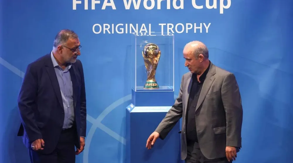 مهدي تاج يقف بجانب «كأس العالم» يمين الصورة (رويترز)