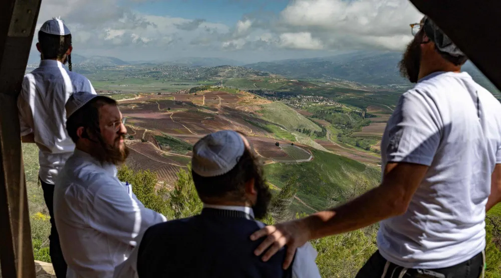 مجموعة من اليهود المتشددين يراقبون آثار القصف على جنوب لبنان من نقطة مشرفة في الجليل الأعلى (أ.ف.ب)