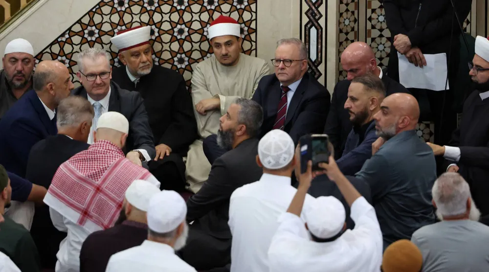 ألبانيزي جالساً وسط الأئمة أثناء زيارته لأكبر مسجد في أستراليا خلال صلاة عيد الفطر (رويترز)