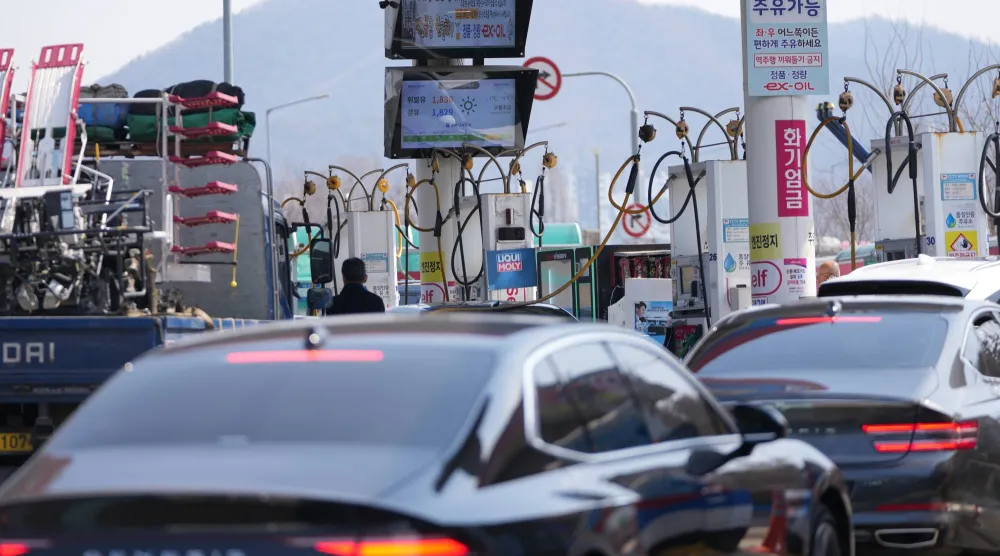 رجل في الوسط يقوم بتعبئة سيارة بالوقود في محطة وقود في سيول (أ.ب)