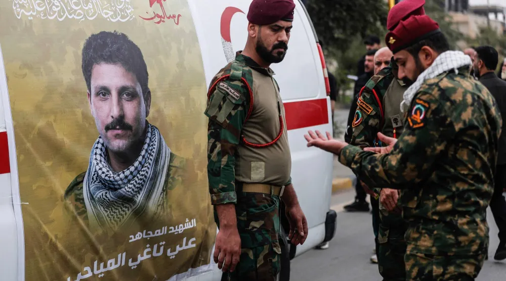 أفراد من «الحشد الشعبي» العراقي بجوار سيارة إسعاف مُغطاة بصورة عنصر منهم قُتل في غارة جوية على صلاح الدين. (أ.ف.ب)