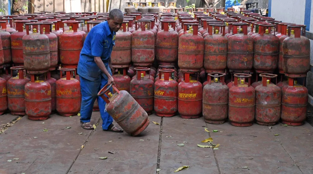 عامل ينقل أسطوانة غاز البترول المسال مملوءة من مستودع في مومباي (د.ب.أ)