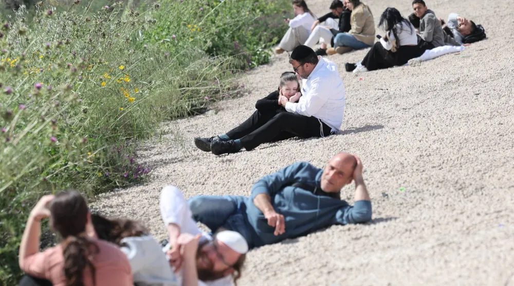 إسرائيلي يحمل ابنته بينما يتبع هو وآخرون تعليمات الجيش الإسرائيلي بالاستلقاء على الأرض مع انطلاق صفارات الإنذار في تل أبيب يوم 20 مارس 2026 (إ.ب.أ)