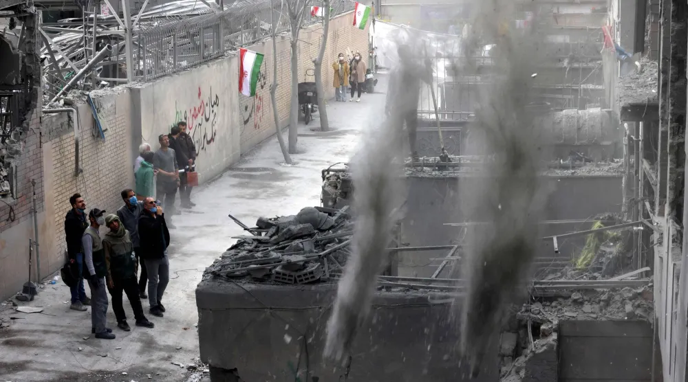 إيرانيون أمام مبنى متضرر من الحرب في العاصمة طهران (أ.ف.ب)