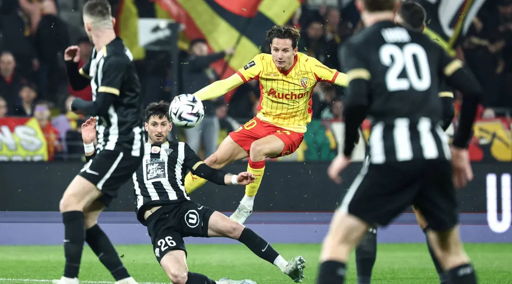 فلوريان توفان لاعب لانس يسدد الكرة بجوار فلوران هانين مدافع أنجيه (أ.ف.ب)