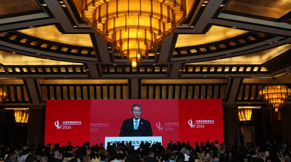 يظهر رئيس الوزراء الصيني لي تشيانغ على شاشة كبيرة خلال إلقائه خطابه في افتتاح منتدى التنمية الصيني (أ.ب)