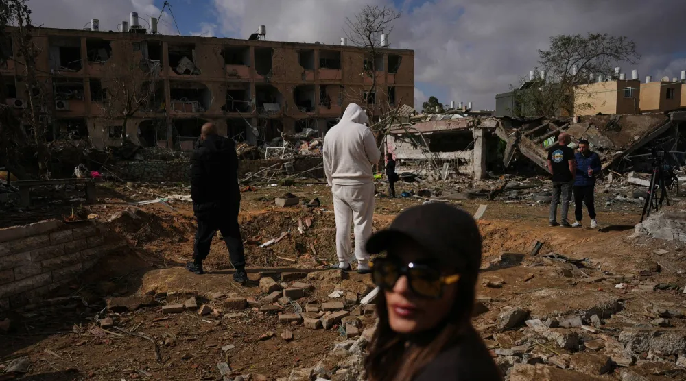 مواطنون يتفقدون أثر سقوط صاروخ إيراني في ديمونة جنوب إسرائيل اليوم (أ.ب)